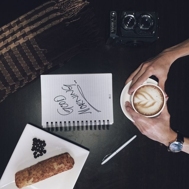 two people meeting over coffee at a cafe table with notebook