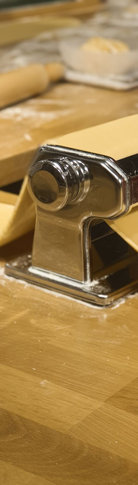 fresh pasta dough and rolling pin on a wooden bench