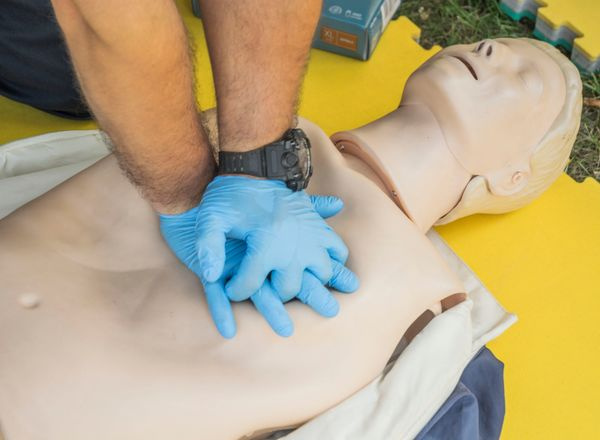 hands performing CPR on manikin first aid training