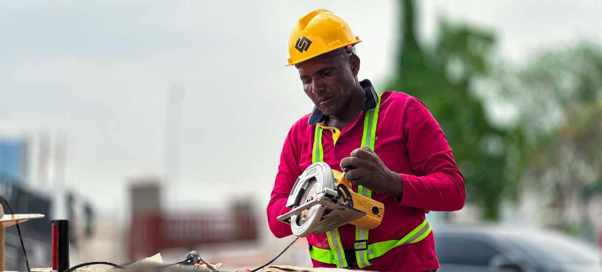 carpenter cutting wood with circular saw at construction site
