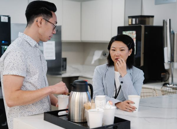 two colleagues discussing over coffee office break room