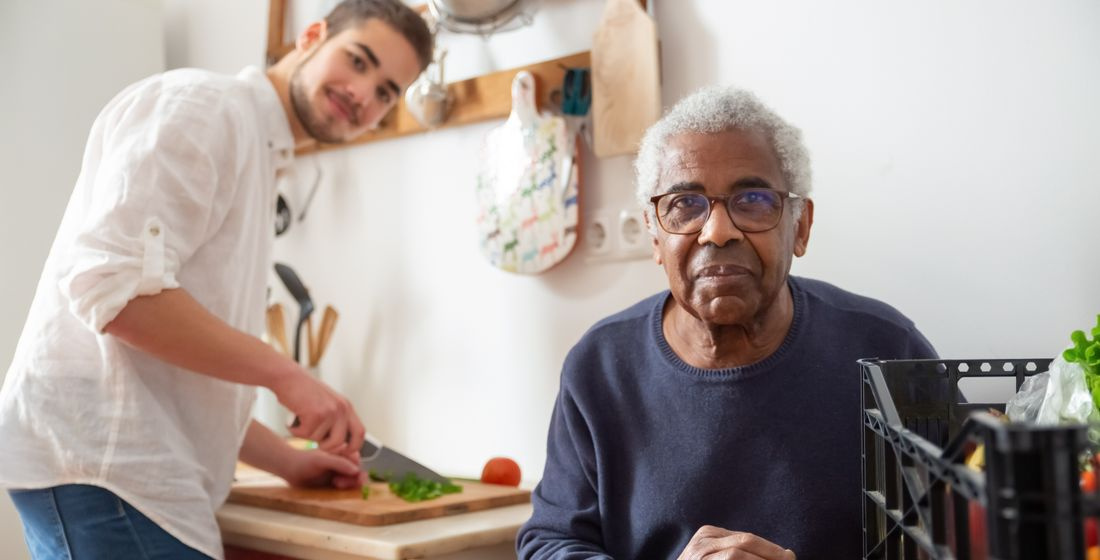 young adult helping senior in kitchen