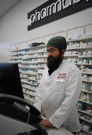 pharmacist at pharmacy counter with medicine shelves