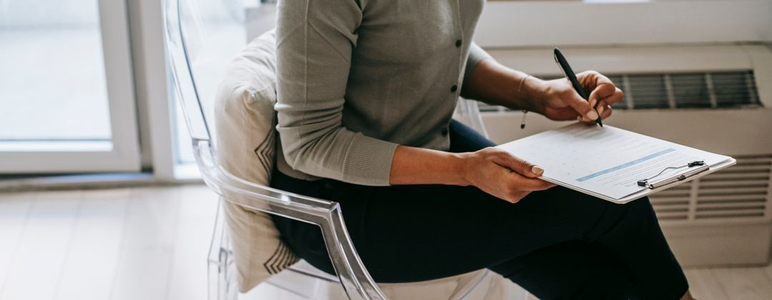 unrecognizable psychologist taking notes on clipboard