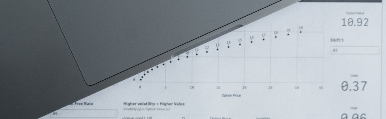 laptop with analytics charts beside printed spreadsheet on desk